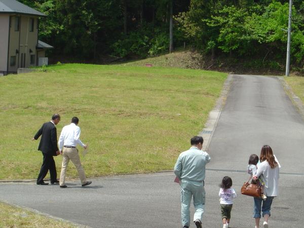 分譲地を見学しに来た女性と子供2人を案内している男性の写真